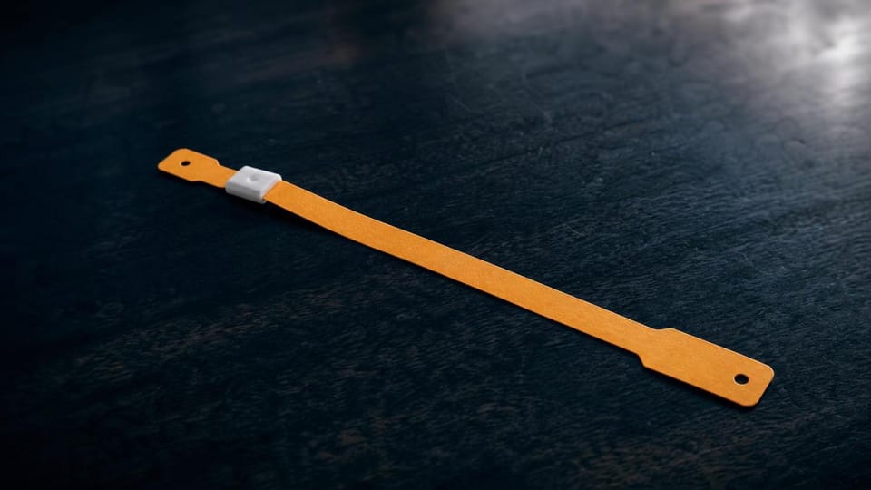 Single unprinted one-use wristband on a dark counter.